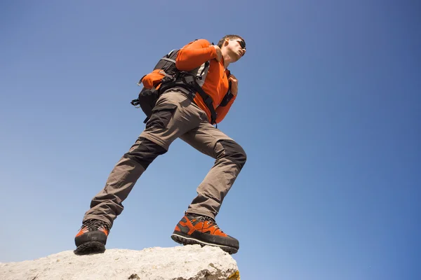 Junger Mann mit Rucksack auf einem Berggipfel an einem sonnigen Tag. — Stockfoto