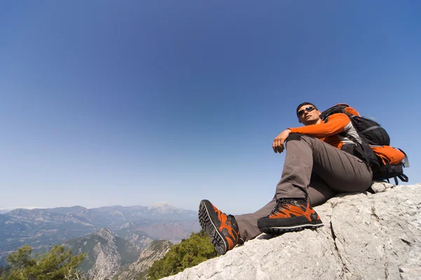 Joven con mochila en la cima de una montaña en un día soleado . — Foto de Stock