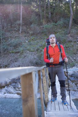 Genç adam bir sırt çantası ile bir dağ nehir taşımak için.