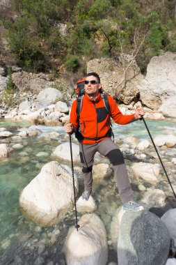 Genç adam bir sırt çantası ile bir dağ nehir taşımak için.
