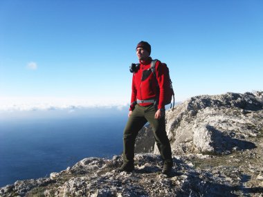 Dağlar ve deniz fon karşı denizde seyir bir uçurumun üzerinde bir adam duruyor.