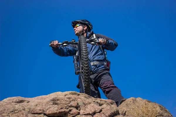 El tipo en la cima de la montaña con la bicicleta. contra el cielo azul . —  Fotos de Stock