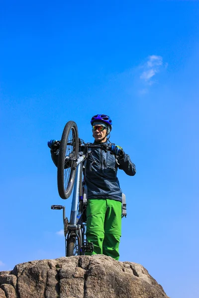 El tipo en la cima de la montaña con la bicicleta. contra el cielo azul . — Foto de Stock