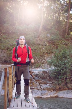 Genç adam bir sırt çantası ile bir dağ nehir taşımak için. 