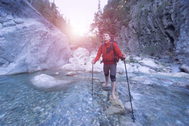 Genç adam bir sırt çantası ile bir dağ nehir taşımak için. 