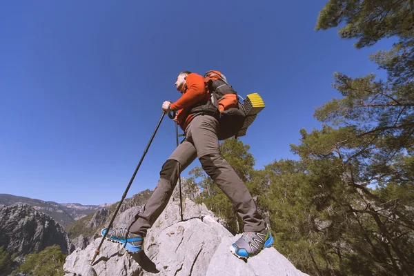 Jeune homme avec sac à dos sur un sommet de montagne par une journée ensoleillée . — Photo