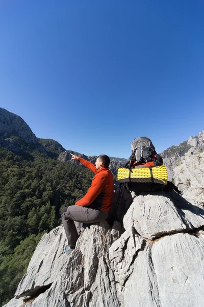 Joven con mochila en la cima de una montaña en un día soleado . — Foto de Stock