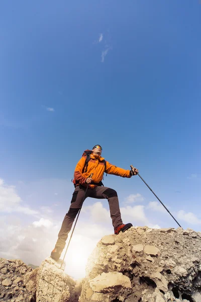Mladý muž s batohem na vrcholu hory za slunečného dne. — Stock fotografie