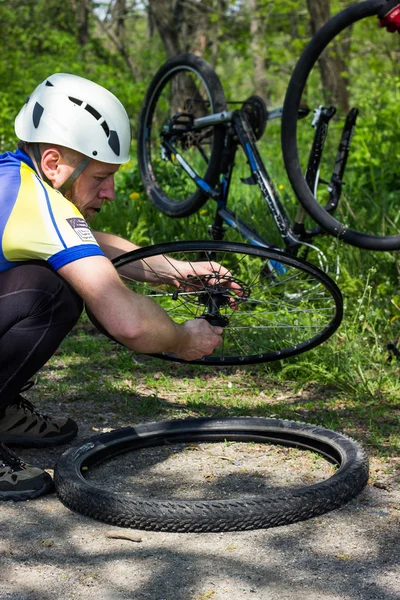 男人在夏天修复车轮在山地自行车的性质. — 图库照片