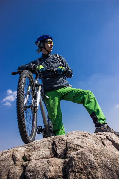 A srác a tetején egy hegy-a kerékpár, a kék ég ellen. — Stock Fotó