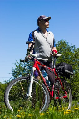 Kırsal kesimde bir dağ bisikleti ile yürüyen adam.