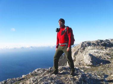 Dağlar ve deniz fon karşı denizde seyir bir uçurumun üzerinde bir adam duruyor.