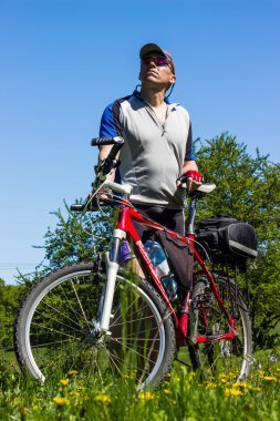 Kırsal kesimde bir dağ bisikleti ile yürüyen adam.