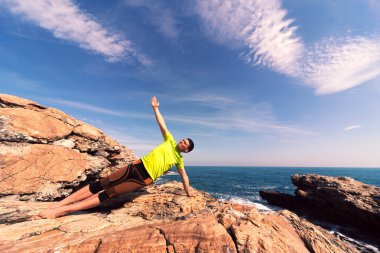 Genç adam plajda yoga egzersizleri yapıyor.. 
