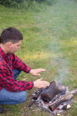Adam ile yaz ormandaki bir kamp ateşi kamp alanında 