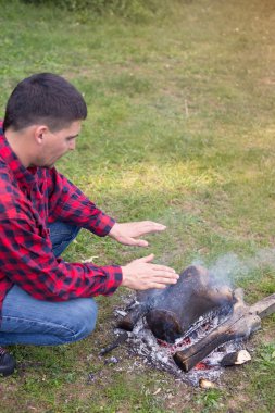 Nehir kıyısında ahşap bir ateşle ormanda kamp. 