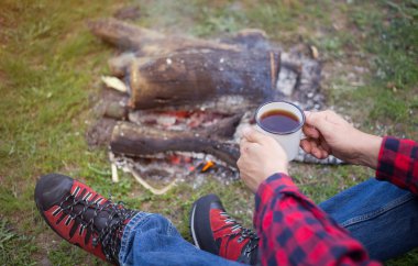 Nehir kıyısında ahşap bir ateşle ormanda kamp. 