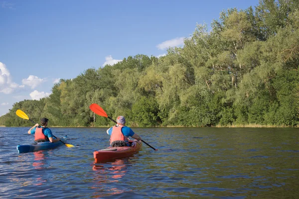 Männer fahren mit dem Kanu auf dem Fluss im Sommer an einem sonnigen Tag. — Stockfoto