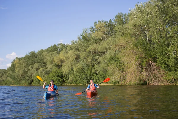 Чоловіки подорожують на каное на річці влітку сонячний день . — стокове фото