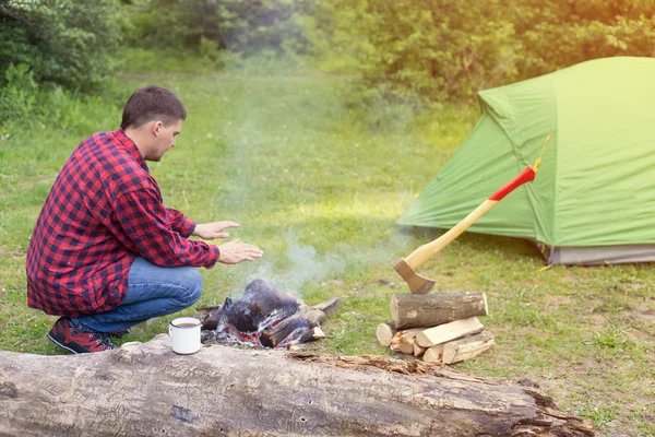 Camping in the woods with a fire in the wood on the bank of the river.