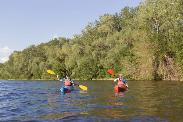 Dos chicos viajan por el río en un kayak en el verano . — Foto de Stock