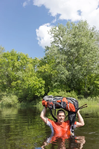 Mann überquert Fluss mit Rucksack. — Stockfoto