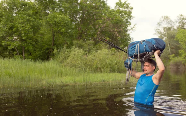 Mann überquert Fluss mit Rucksack. — Stockfoto