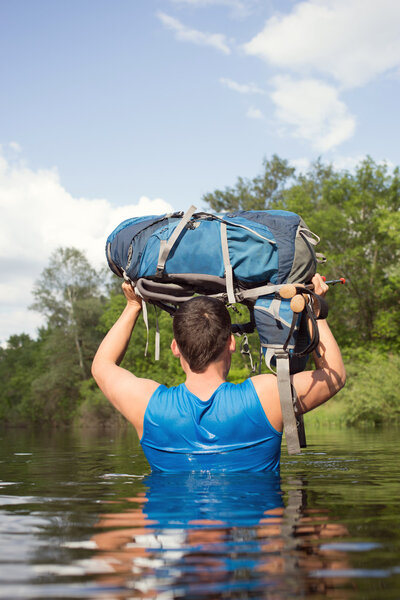 Человек, переходящий реку с рюкзаком
.