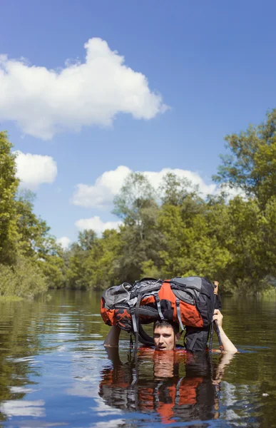 Homme traversant la rivière avec un sac à dos . — Photo