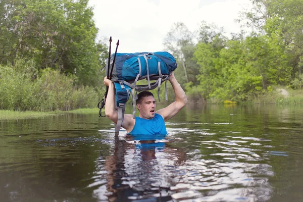 Mann überquert Fluss mit Rucksack. — Stockfoto