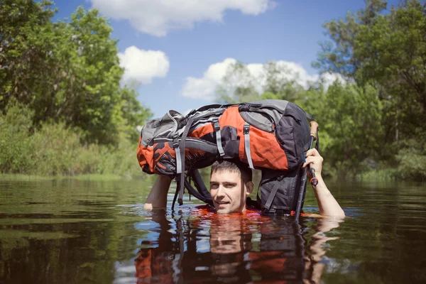 Mann überquert Fluss mit Rucksack. — Stockfoto