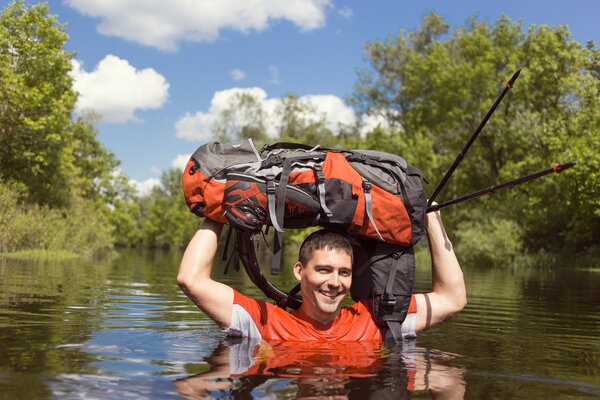 Man crossing the river with a backpack.