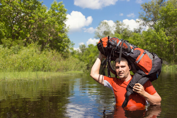 Человек, переходящий реку с рюкзаком
.