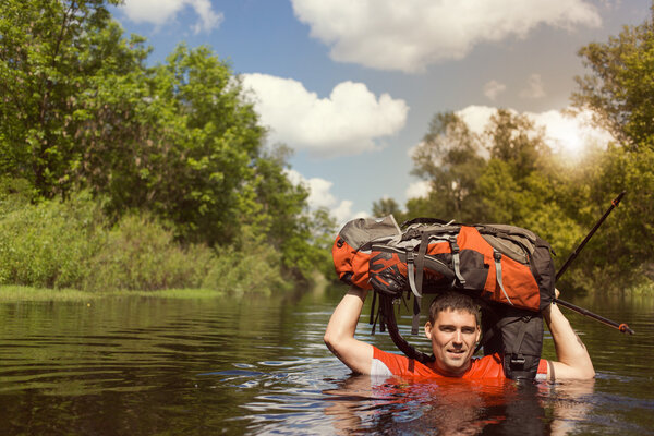 Человек, переходящий реку с рюкзаком
.