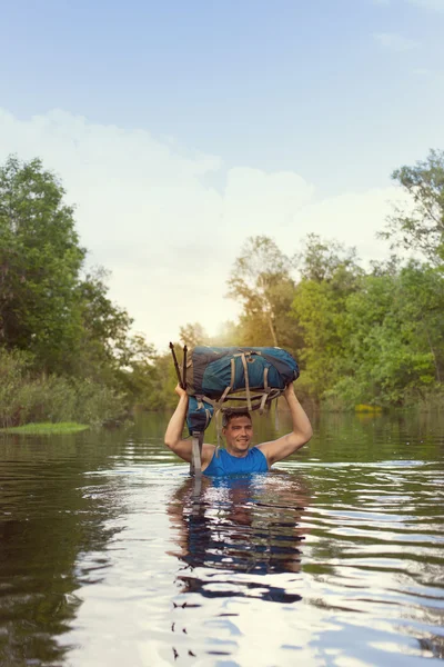 Mann überquert Fluss mit Rucksack. — Stockfoto
