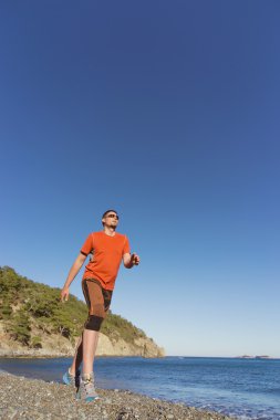 Güneşli bir deniz kıyısından çalışan adam.