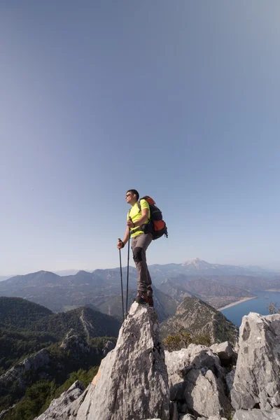 Νεαρό άνδρα με σακίδιο στην κορυφή ενός βουνού. — Φωτογραφία Αρχείου