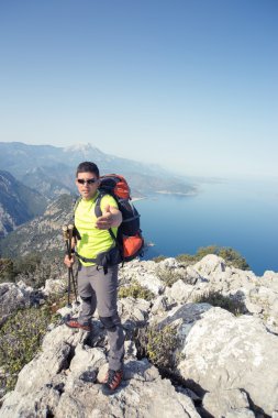 Dağın tepesinde sırt çantası ile genç adam .