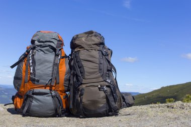 Mavi gökyüzüne karşı dağlarda sırt çantaları ile kamp.