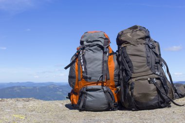 Mavi gökyüzüne karşı dağlarda sırt çantaları ile kamp.