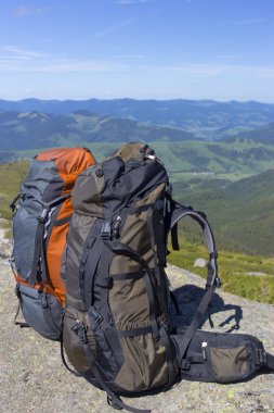 Mavi gökyüzüne karşı dağlarda sırt çantaları ile kamp.