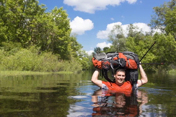 Homme traversant la rivière avec un sac à dos . — Photo