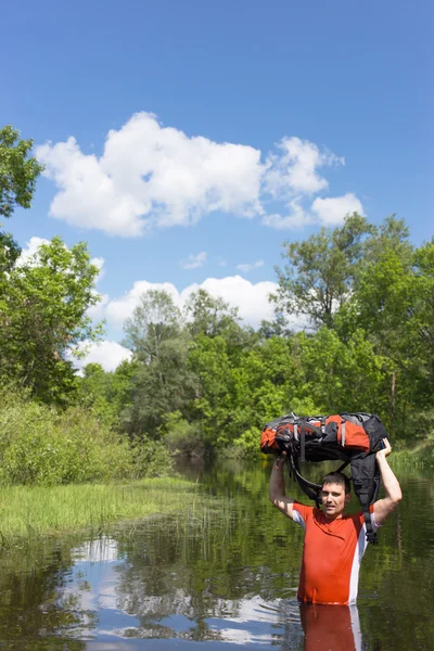 Mann überquert Fluss mit Rucksack. — Stockfoto