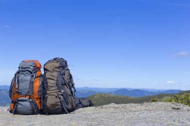 Mavi gökyüzüne karşı dağlarda sırt çantaları ile kamp.