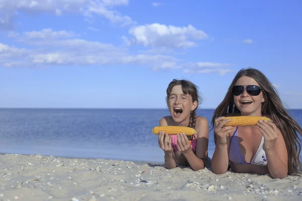 Happy children on the beach eating sweet corn. — Stock Photo, Image