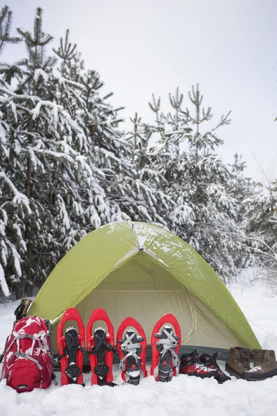 Camping i tält i skogen med en ryggsäck och snöskor. — Stockfoto