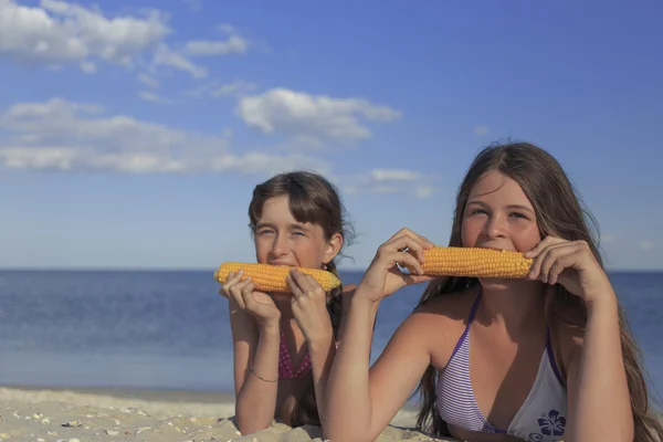Happy children on the beach eating sweet corn. — Stock Photo, Image