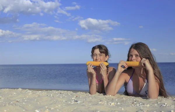 Happy children on the beach eating sweet corn. — Stock Photo, Image