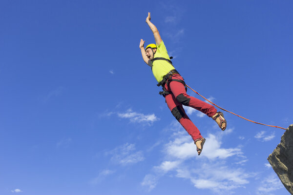Перейти веревку с высокой скалы в горах
. 