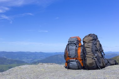 Mavi gökyüzüne karşı dağlarda sırt çantaları ile kamp.